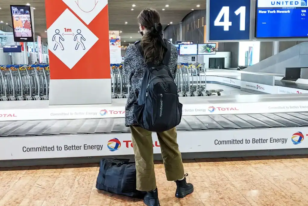 Woman with backpack at airport baggage claim, traveling from the U.S.